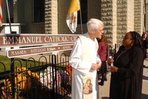 Precious Blood Father Angelo Anthony, pastor of Emmanuel Parish, speaks with a parishioner in front of the church.