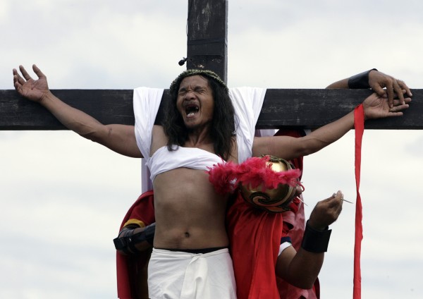 Penitent reacts as nails are removed from his palms after being nailed on wooden cross in 2009 Good Friday ritual in Philippines