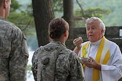 Military chaplain seves Communion in 2011 at Camp Buckner in West Point, N.Y. Augustinian Father Edson Wood, brigade chaplain at the U.S. Military Academy, distributes Communion during Mass at Camp Buckner in West Point, N.Y., in 2011. (CNS photo/Gregory A. Shemitz)