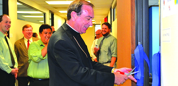 Archbishop Dennis M. Schnurr cuts a ribbon at a July 14 ceremonial opening of the NET Ministries regional office located in downtown Cincinnati while archdiocesan staff look on. The archbishop also read a prayer and blessed the new office. (CT Photo/John Stegeman)