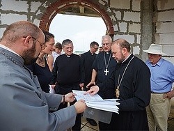 Father Ihor Tabaka shows Bishop Vasyl Tuchapets of Kharkiv, Ukraine, Archbishop Blase J. Cupich of Chicago and Archbishop Joseph E. Kurtz of Louisville, Ky., president of the U.S. Conference of Catholic Bishops, plans of a future church in Lubotyn, Ukraine, June 21. (CNS photo/Sergey Kozlov)