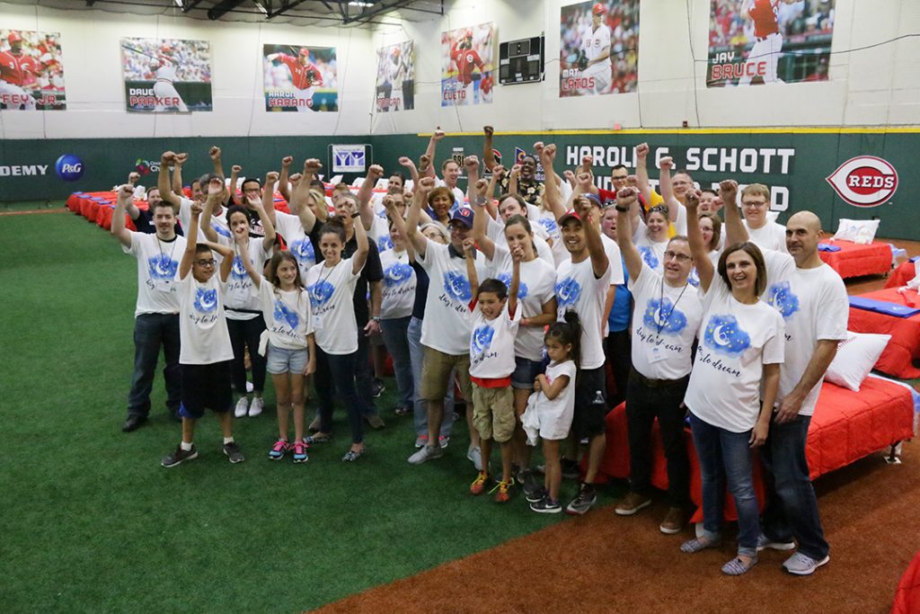 Some of the 100 volunteers from local companies declare victory after assembling and making the beds set up at the P&G Cincinnati MLB Youth Academy the night before the event. Volunteers from the City Dash courier company and members of Crossroad Church’s “Mighty Men” delivered every bed by Saturday night, so that each child who received one went to sleep in it. (Courtesy Photo)