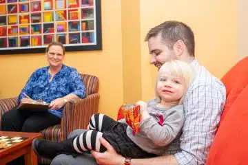 Man holding child on his lap while supervised